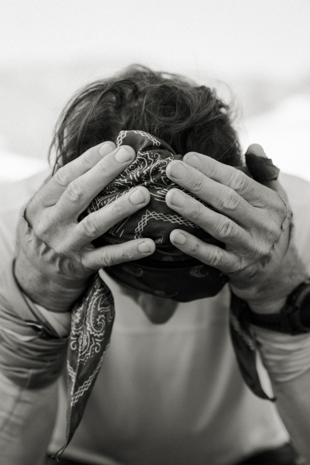 Black-and-white portrait with hands covering the head
